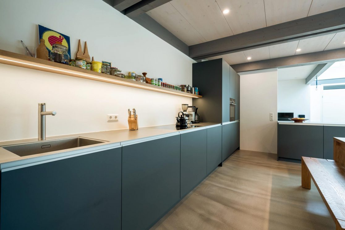 Küche mit Spüle sowie Einbauschränke und Esstisch mit Bank