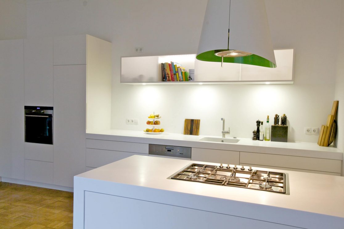 Kochfeld in weiß vor weißer Küchenfront und beleuchtetem Hängeregal