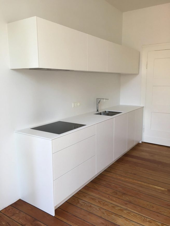 Kochfeld und Spüle in weißer Küchenfront mit weißem Hängeregal